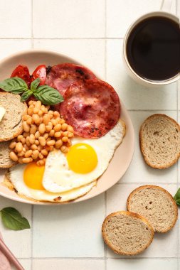 Lezzetli İngiliz kahvaltısı ve beyaz fayanslı bir fincan kahve.