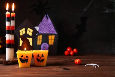 Farklı yanan mumlar ve ahşap masada Cadılar Bayramı dekoru olan kompozisyon