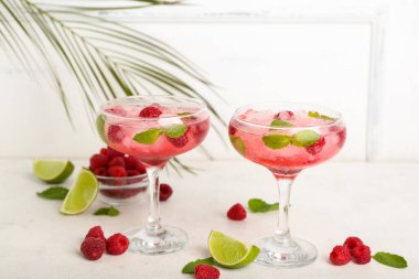 Taze ahududu mojito bardakları ve beyaz arka planda böğürtlenli kase.