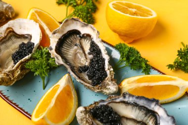 Sarı arka planda limonlu ve siyah havyarlı lezzetli istiridye tabağı.