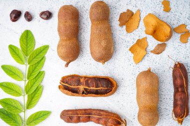 Beyaz arka planda lezzetli tamarindler, kabuk, tohumlar ve yapraklar