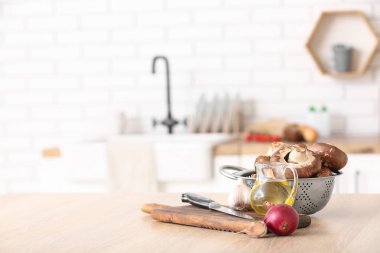 Taze mantarlı kolatör ve mutfak masasında pişirme aletleri.