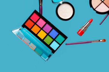 Mavi arka planda uçan dekoratif kozmetik ürünleri