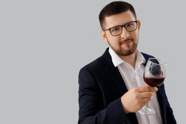 Gri arka planda şarap kadehi olan genç şarap garsonu.