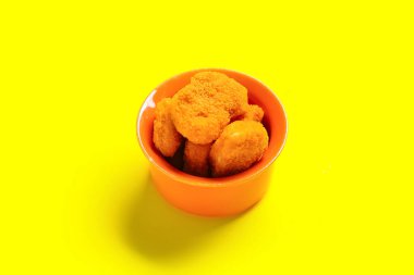 Sarı arka planda lezzetli nuggetlarla dolu bir kase