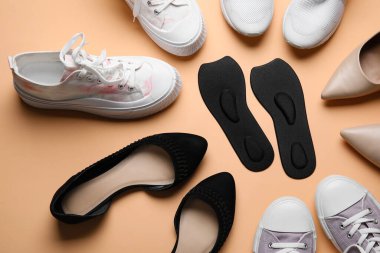 Bej arka planda farklı spor ayakkabıları, ayakkabıları ve ortopedik tabanları olan kompozisyon