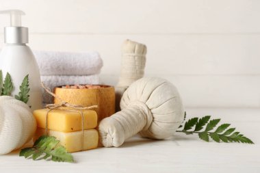 Hafif arkaplanda kaplıca aksesuarları ve bitki yapraklarıyla kompozisyon