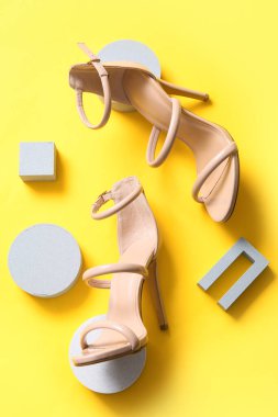Composition with stylish female shoes and plaster decor on yellow background