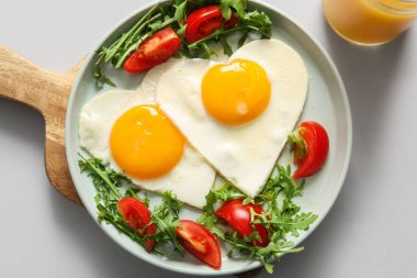 Lezzetli yumurta, domates, roka ve beyaz arka planda bir bardak meyve suyu, yakın plan.