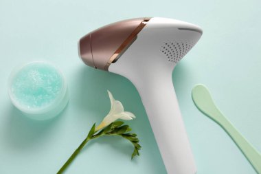 Turkuaz arka planda bir kavanoz fırça ve çiçek ile modern fotoepilatör