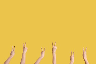 Sarı arka planda barış hareketlerini gösteren kadın elleri