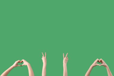 Yeşil arka planda barış ve kalp hareketleri gösteren kadın elleri