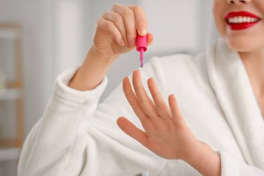 Güzel, genç, mutlu bir kadın banyoda manikür yapıyor.