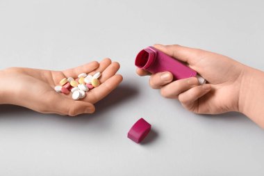 Astım spreyli çocuk elleri ve beyaz arka planda haplar.