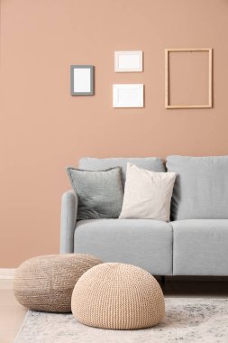 Oturma odasının içinde kanepe, puf ve boş fotoğraf çerçeveleri var.