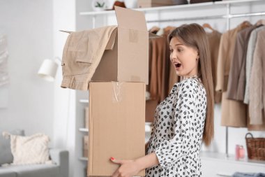 Soyunma odasında elbise kutularıyla şok olmuş güzel genç bir kadın.