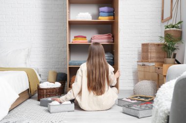 Genç bir kadın, temiz giysileri dolaba katlıyor.