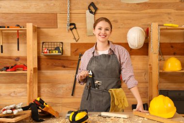 Atölyede aletleri olan genç bir kadın marangoz. İşçi Bayramı kutlamaları