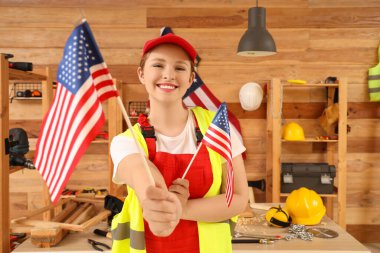 Atölyede ABD bayraklı genç bayan marangoz. İşçi Bayramı kutlamaları