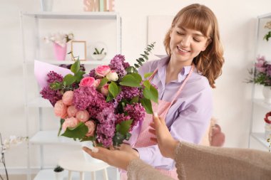 Mağazadaki müşteriye leylak desenli çiçek veren kadın.