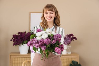Çiçekçide çiçek buketi, leylak ve kasımpatı tutan kadın.