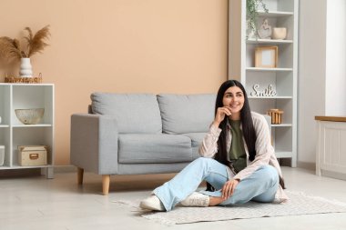 Gri koltuğun yanında, şık oturma odasında dinlenen güzel bir genç kadın.