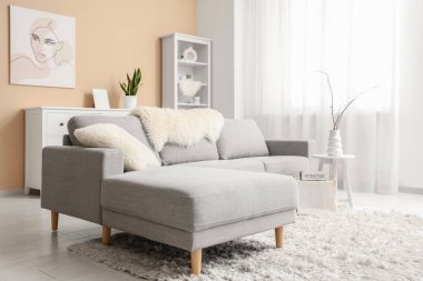 Gri kanepesi, sehpası, raf ünitesi ve resmi olan şık bir oturma odası.