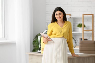 İş yerinin yakınında tablet kullanan hamile bir iş kadını.