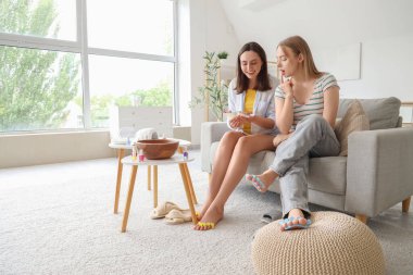 Oturma odasında pedikür için oje rengini seçen genç bir kadın.