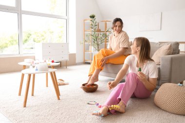 Kozmetik yağlı genç kadınlar oturma odasında pedikür yapıyorlar.