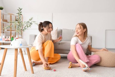 Oturma odasında pedikür yapan genç kadınlar.