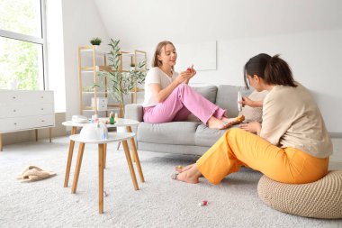 Oturma odasında pedikür yapan genç kadınlar.