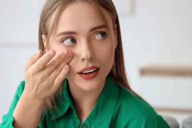 Evde kontak lens takan genç bir kadın, yakın plan.