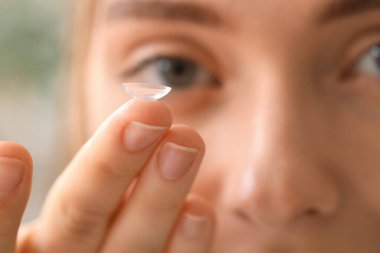 Evde kontak lensli genç bir kadın, yakın plan.