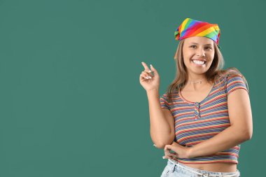 Genç bir kadın yeşil arka plandaki bir şeyi işaret ediyor.