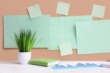 Boş kağıtlar ve bej duvarın yanındaki masada diyagramı olan çimenler. Yeşil Enerji kavramı