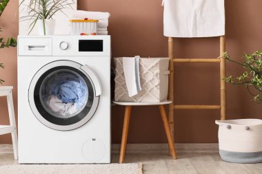 Çamaşır makinesi, sepeti ve merdiveni olan çamaşır odasının içi.