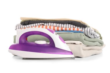 Beyaz arka planda izole edilmiş temiz giysi yığınına sahip modern demir.