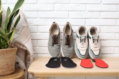 Ortopedik tabanlı spor ayakkabılar koridordaki beyaz tuğla duvarın yanındaki bankta.