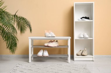 Koridordaki bej duvarın yanındaki bankta ortopedik tabanlı spor ayakkabılar.