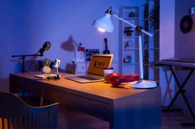 Podcaster 'ın iş yeri. Karanlık stüdyoda dizüstü bilgisayarlar, mikrofonlar ve parlayan lambalar.