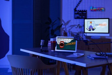 Podcaster 'ın iş yeri. Karanlık stüdyoda dizüstü bilgisayarı ve mikrofonları var.