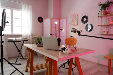 Podcaster 'ın atölyesinin içinde iş yeri, vinil diskler ve katlanır ekran var.