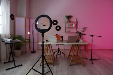 Podcaster 'ın atölyesinin içinde iş yeri, vinil diskler ve katlanır ekran var.