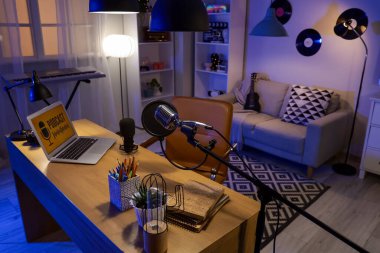 Podcaster 'ın iş yeri. Karanlık stüdyoda dizüstü bilgisayarı ve parlak lambaları var.