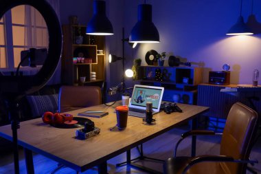 Podcaster 'ın iş yeri, raf üniteleri ve parlayan lambaları olan karanlık stüdyonun içi.