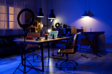 Podcaster 'ın iş yeri, raf üniteleri ve parlayan lambaları olan karanlık stüdyonun içi.