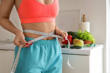 Mutfakta belini ölçen genç bir kadın. Diyet kavramı