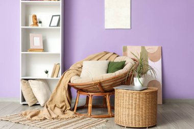 Odanın içinde, menekşe duvarın yanında rahat bir koltuk, masa ve raf var.