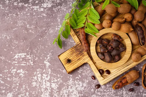 Ahşap tahta tahta ve gri arka planda lezzetli tamarindler.